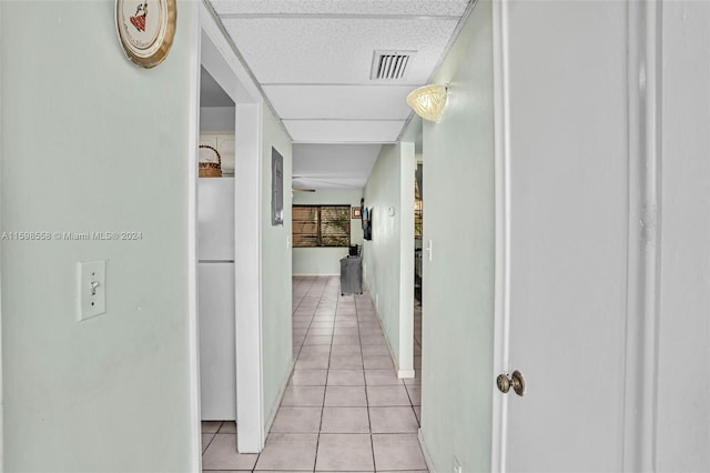 hallway featuring a drop ceiling and light tile patterned flooring