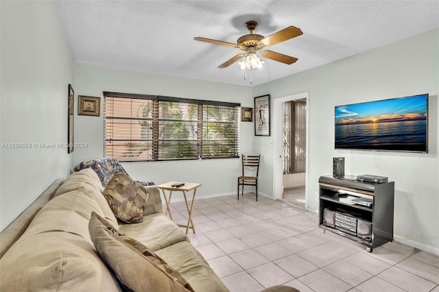 living room with ceiling fan, light tile patterned floors, and a textured ceiling