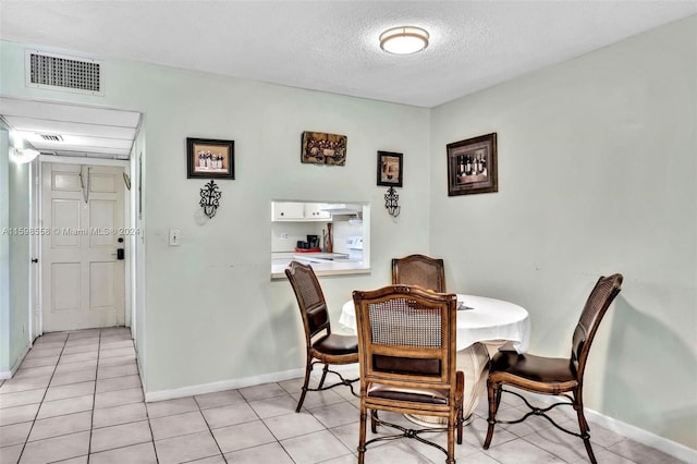 tiled dining space featuring a textured ceiling