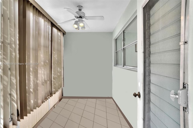 interior space with ceiling fan, wooden walls, and light tile patterned flooring