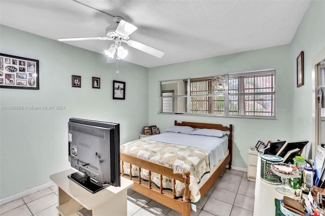 bedroom featuring ceiling fan, light tile patterned flooring, and a textured ceiling