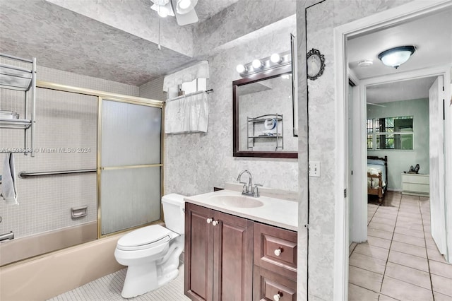 full bathroom featuring vanity, tile patterned floors, combined bath / shower with glass door, ceiling fan, and toilet