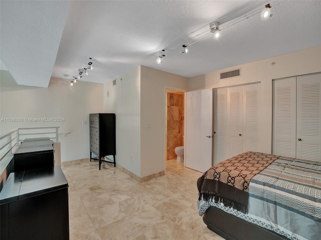 bedroom featuring two closets, a textured ceiling, and ensuite bathroom