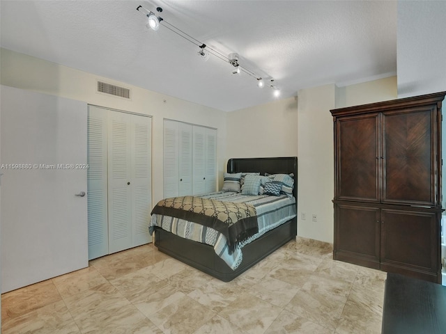 bedroom featuring multiple closets and rail lighting