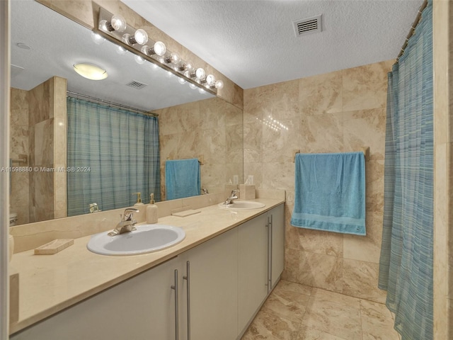 bathroom featuring vanity, tile walls, a textured ceiling, and walk in shower