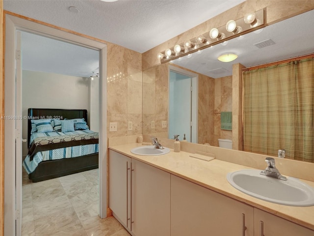 bathroom featuring tile walls, vanity, toilet, a textured ceiling, and a shower with shower curtain