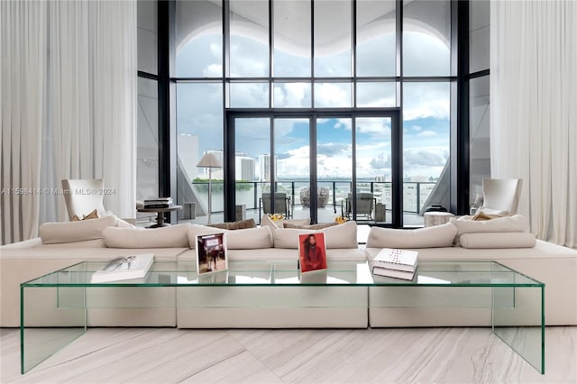 living room featuring plenty of natural light, a wall of windows, and a towering ceiling