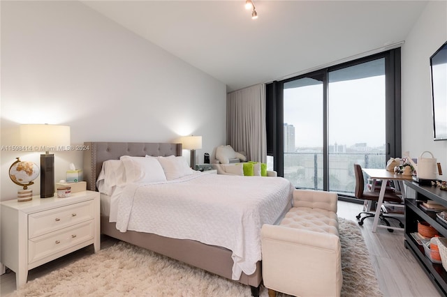 bedroom featuring light hardwood / wood-style flooring, expansive windows, and lofted ceiling