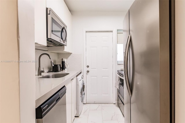 kitchen with sink, appliances with stainless steel finishes, white cabinetry, washer / clothes dryer, and decorative backsplash