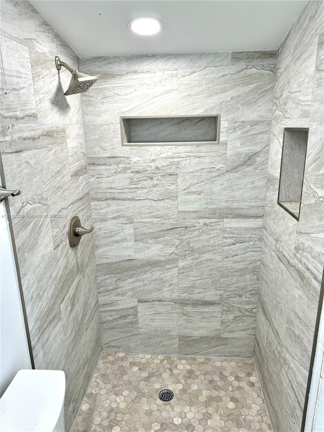 bathroom featuring tiled shower and toilet