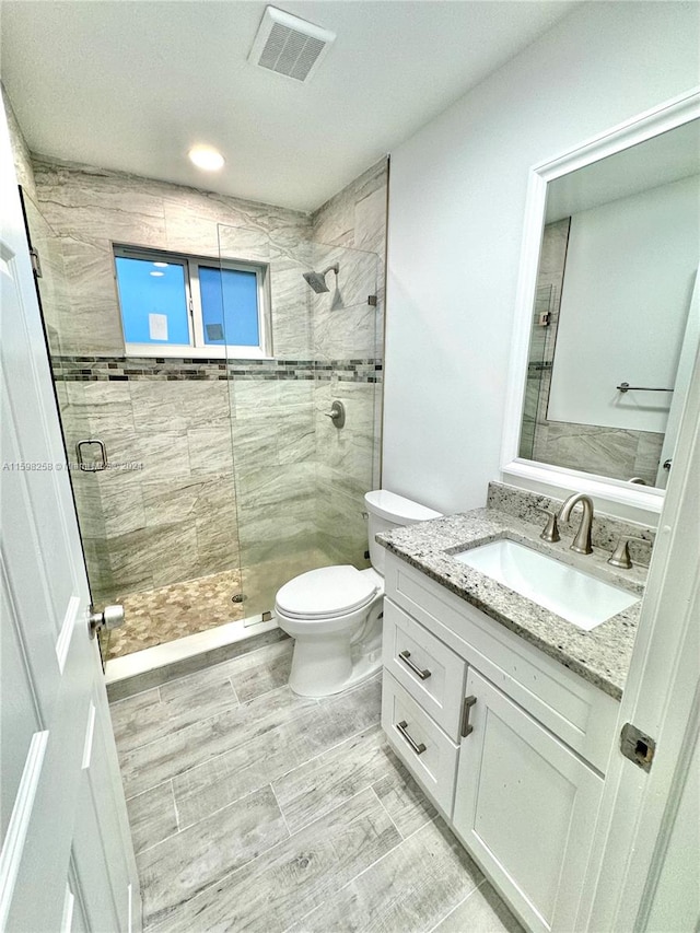 bathroom with vanity, walk in shower, and toilet