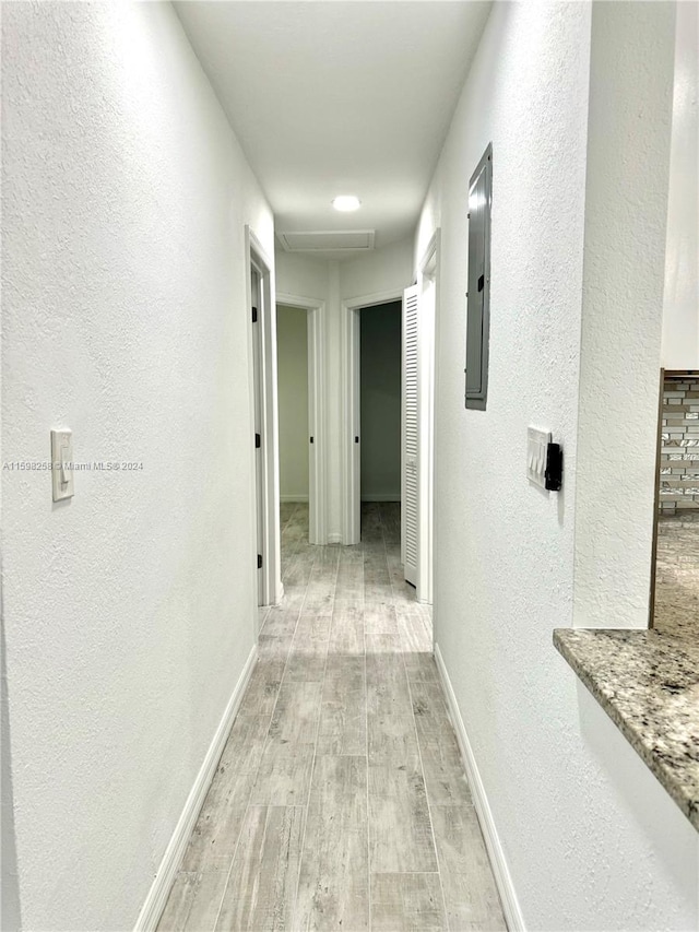 hallway with light hardwood / wood-style floors and electric panel