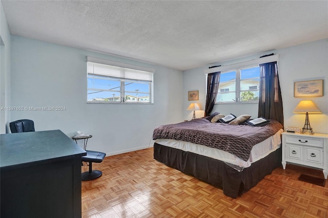 bedroom featuring light parquet flooring, a textured ceiling, and multiple windows