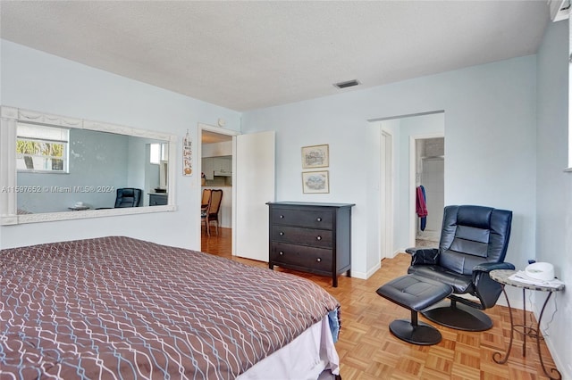 bedroom featuring light parquet floors and a textured ceiling