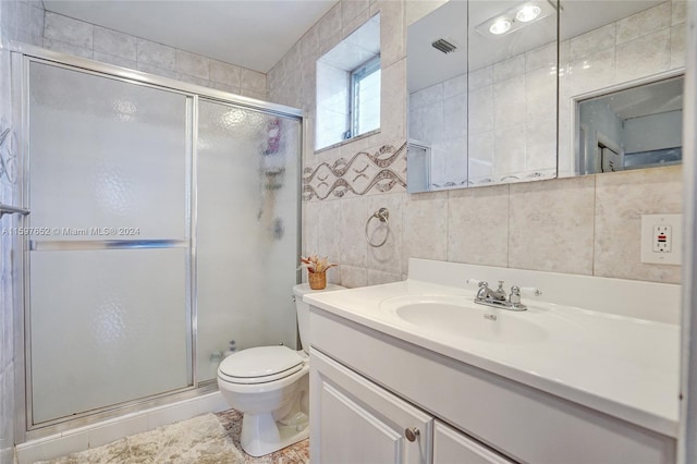 bathroom with a shower with shower door, toilet, tasteful backsplash, tile walls, and vanity