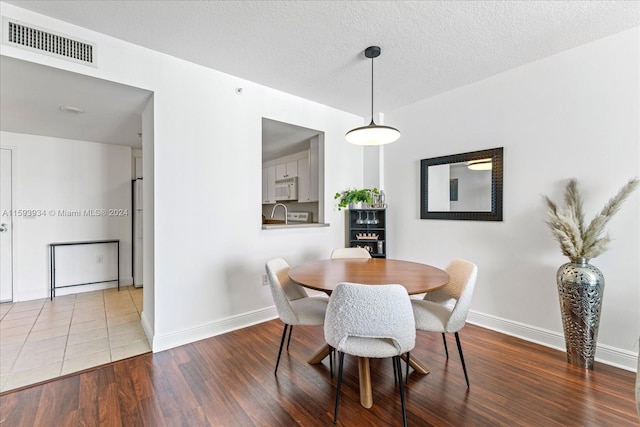 dining room with wood-type flooring and a textured ceiling