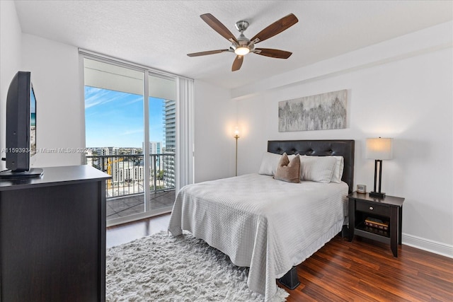 bedroom with access to exterior, ceiling fan, dark hardwood / wood-style flooring, expansive windows, and a textured ceiling