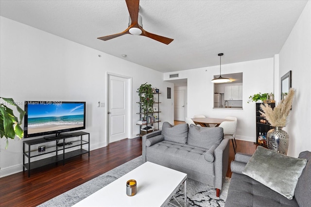 living room with a textured ceiling, dark hardwood / wood-style floors, and ceiling fan