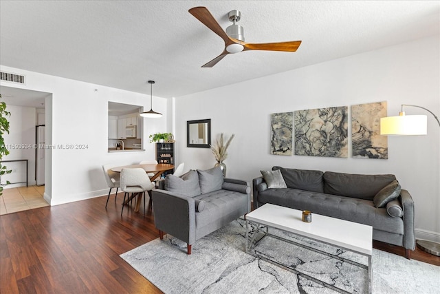 living room featuring a textured ceiling, hardwood / wood-style flooring, and ceiling fan