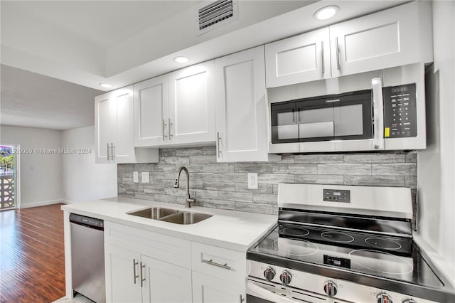 kitchen featuring sink, decorative backsplash, white cabinetry, wood-type flooring, and stainless steel appliances