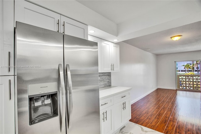 kitchen featuring white cabinets, stainless steel fridge, tasteful backsplash, and dark wood-type flooring