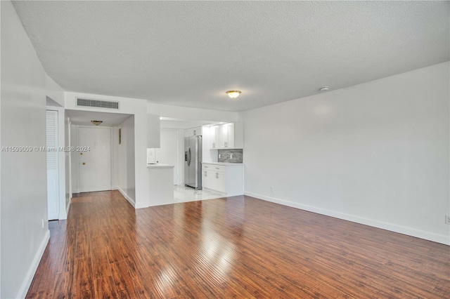 unfurnished living room featuring wood-type flooring and a textured ceiling