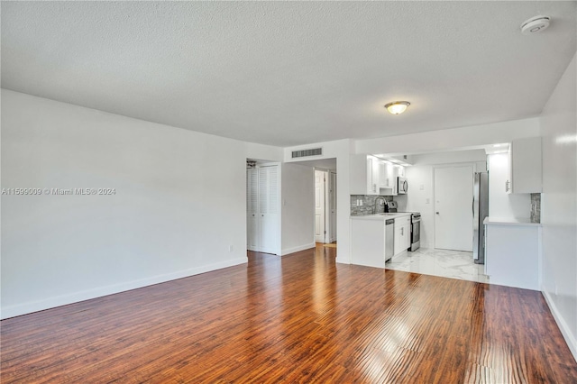 unfurnished living room with wood-type flooring, a textured ceiling, and sink