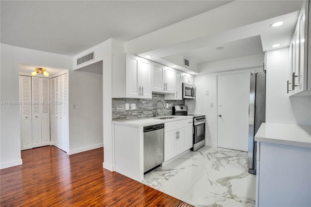 kitchen with sink, stainless steel appliances, decorative backsplash, white cabinets, and light wood-type flooring