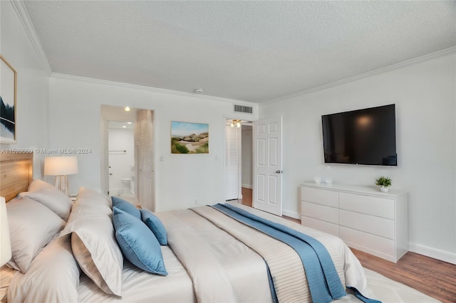 bedroom with a textured ceiling, connected bathroom, hardwood / wood-style flooring, and crown molding