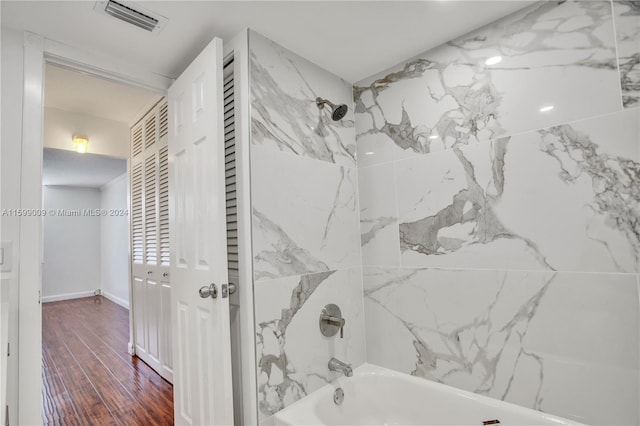 bathroom featuring wood-type flooring and tiled shower / bath combo