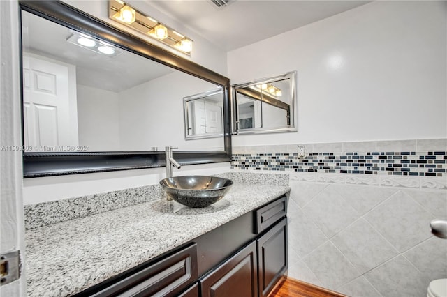 bathroom featuring vanity and tile walls