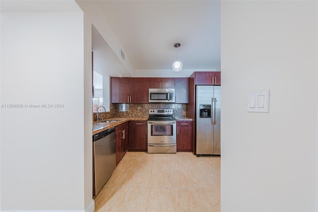 kitchen with light stone countertops, appliances with stainless steel finishes, tasteful backsplash, sink, and decorative light fixtures