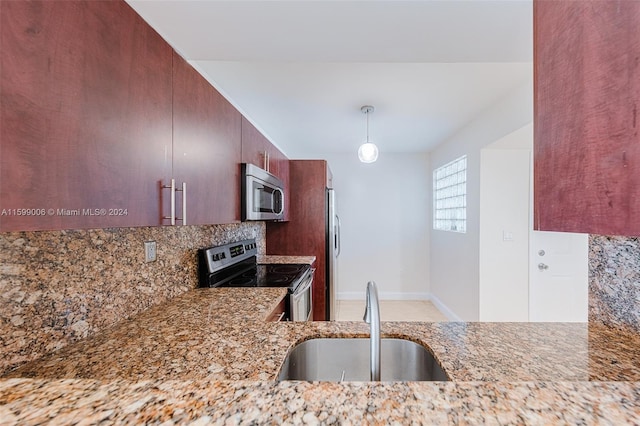 kitchen featuring light stone countertops, sink, hanging light fixtures, backsplash, and appliances with stainless steel finishes