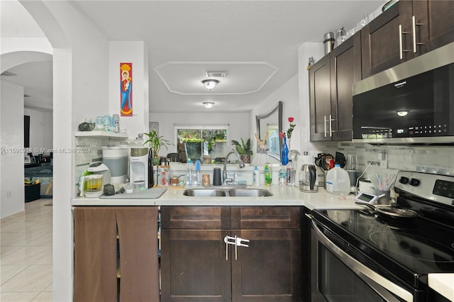 kitchen featuring appliances with stainless steel finishes, sink, backsplash, light tile patterned floors, and dark brown cabinetry