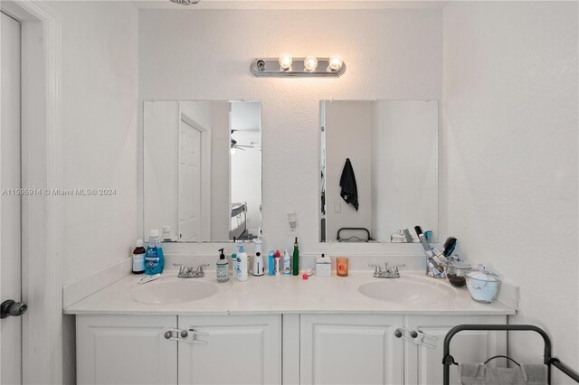 bathroom featuring vanity with extensive cabinet space, double sink, and ceiling fan