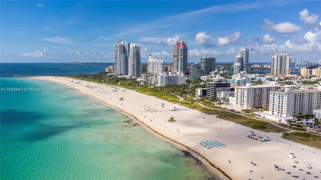 drone / aerial view featuring a water view, a view of city, and a beach view