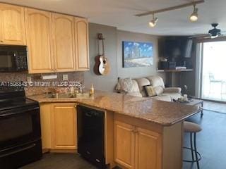 kitchen featuring light brown cabinetry, a peninsula, a ceiling fan, a kitchen bar, and black appliances