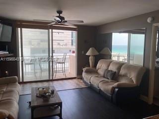 living room featuring wood-type flooring, ceiling fan, plenty of natural light, and a water view