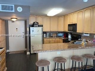 kitchen featuring light stone counters, kitchen peninsula, white fridge, electric range oven, and light brown cabinets