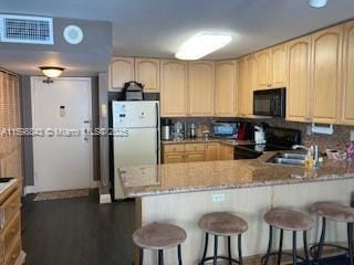 kitchen featuring a peninsula, black appliances, and light brown cabinets