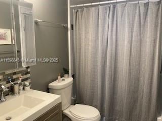 full bathroom featuring toilet, a shower with shower curtain, and vanity