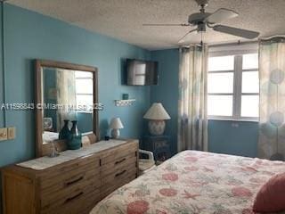 bedroom with a ceiling fan, a textured ceiling, and multiple windows