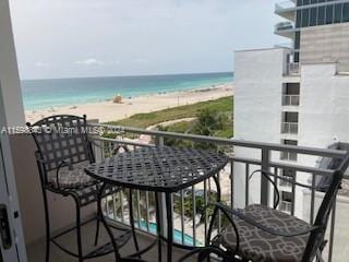 balcony featuring a view of the beach and a water view