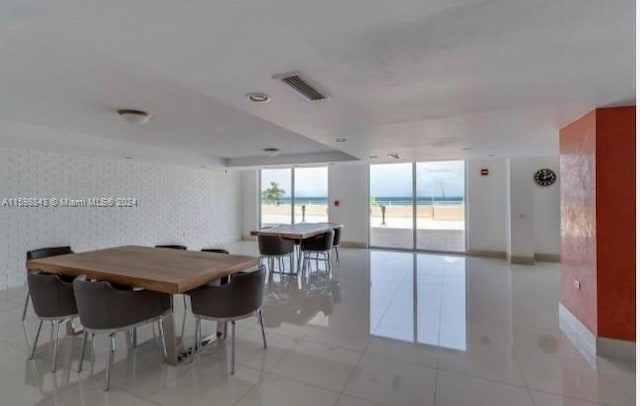 dining room with a wall of windows, light tile patterned flooring, and a water view