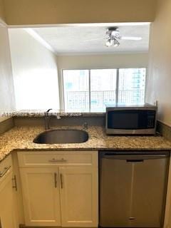 kitchen with stainless steel appliances, sink, light stone countertops, and ornamental molding