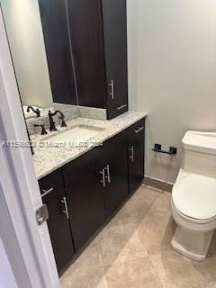 bathroom featuring tile floors, vanity, and toilet