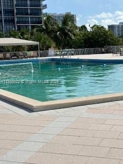 community pool with a patio area and fence