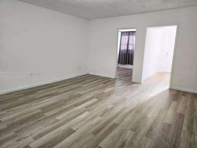 spare room featuring hardwood / wood-style floors and a textured ceiling