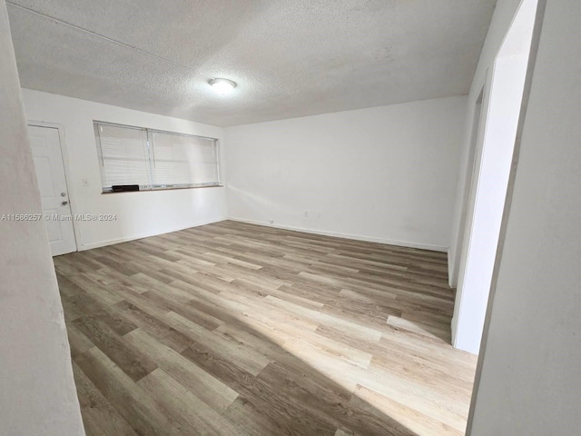 spare room with a textured ceiling and hardwood / wood-style flooring