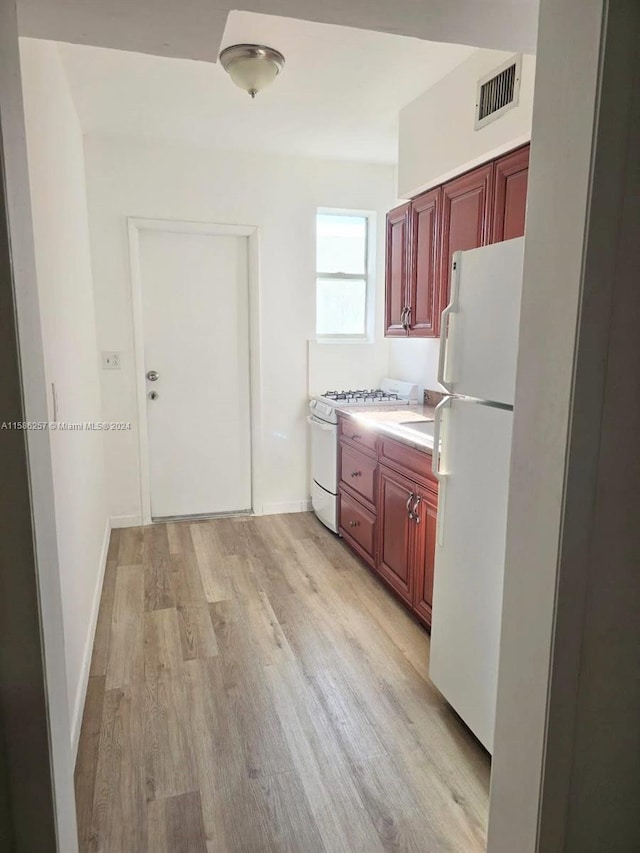 kitchen with light wood-type flooring and white appliances